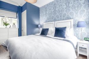圣安德鲁斯Deluxe Penthouse Apartment w Roof Terrace的蓝色的卧室设有白色的床和蓝色的墙壁