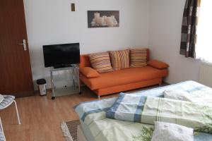 Gnas齐默斯蒂格旅馆的客厅配有橙色沙发和平面电视。