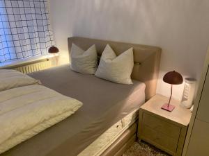 孔恩斯灵比Eremitageparken的一张带白色枕头的床和一张带台灯的桌子