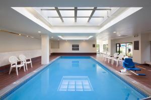 罗切斯特卡勒旅馆及套房酒店的一个带椅子和桌子的大型室内游泳池