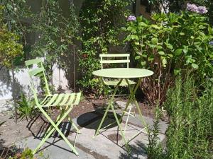 洛索内LA TICINELLA的花园内摆放着两把绿色椅子和一张桌子及椅子