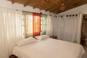 圣克里斯托瓦尔Ideal y linda casita en San Cristóbal-Galápagos的一间卧室配有一张带白色床单和窗户的床。