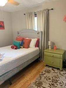 石头山Jackson’s Stone Mountain Hideaway的一间卧室配有一张带色彩缤纷枕头的床和床头柜。