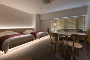 京都Design Hotel Kyoto Fuyacho的一间卧室配有两张床和一张桌子及椅子