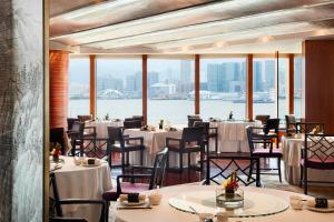 香港香港四季酒店的一间带桌椅并享有水景的餐厅