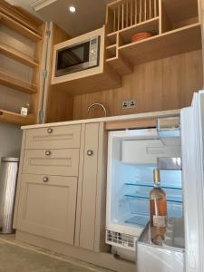 吉林汉姆Wyke Cowsheds的厨房配有开放式冰箱,提供一瓶葡萄酒