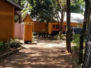 基苏木Mamba Village Kisumu的一座带栅栏和树木的房子的入口