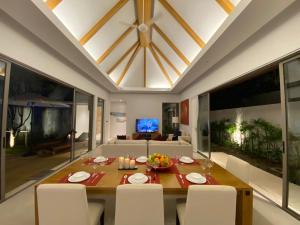 普吉镇Anchan Grand Residence Villa的一间带桌子和白色椅子的用餐室