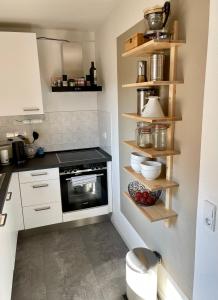 莱比锡Modern, gemütlich, sehr zentrumsnah & ruhig的厨房配有白色橱柜和黑烤箱。