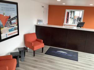 斯波坎Howard Johnson by Wyndham Spokane的一间备有橙色椅子和柜台的等候室