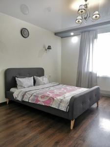 苏梅Lavina apartments的卧室内的一张床铺,墙上挂着一个时钟