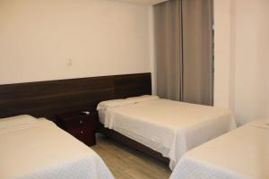 瓜亚基尔DC Suites Aeropuerto的一间设有两张带白色床单的床的房间