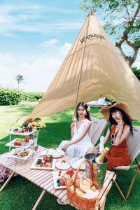 三亚三亚亚龙湾天域度假酒店（接机+林荫泳池）的两个女人坐在野餐桌上吃点东西