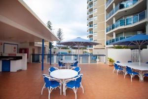 黄金海岸Grosvenor Beachfront Apartments Surfers Paradise的一个带桌椅和蓝伞的庭院