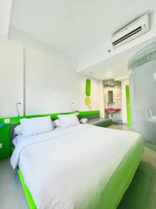 泗水POP！古本酒店的绿色调客房内的一张大型白色床