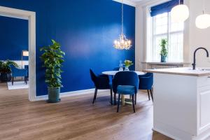 Augustenborg'Gem Suites Luxury Holiday Apartments的一间拥有蓝色墙壁和桌椅的用餐室