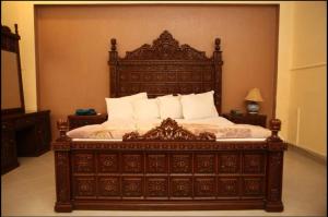 木尔坦Hotel OR Odyssey Residence的卧室内一张带白色枕头的大型木床