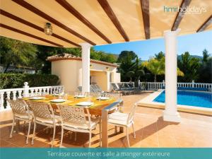 特乌拉达Villa Zacorri - HMR Holidays Moraira的一个带游泳池的庭院里的一张木桌和椅子