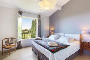 马莱莫尔Villa Briali Pont Royal的一间卧室配有一张带窗户和椅子的床