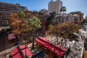 卡斯特利翁-德拉普拉纳Suites Castellón的一条有红遮阳篷和棕榈树的城市街道