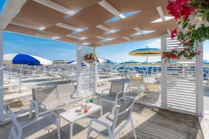 米兰马瑞提那阿德里亚酒店的一个带桌椅和遮阳伞的海滩
