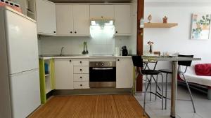 厄尔梅达诺Alquilaencanarias-Medano, Cabezo beach & pool的厨房配有白色橱柜、桌子和冰箱。
