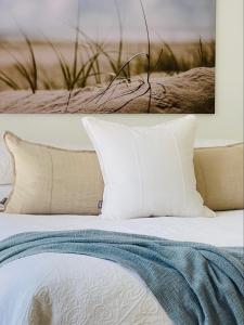科夫斯港Sensom Luxury Boutique Bed and Breakfast的一张带白色枕头的床和一张墙上的照片