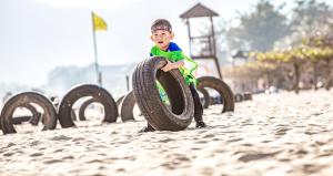 三亚三亚亚龙湾天域度假酒店（接机+林荫泳池）的一名在海滩上玩轮胎的男孩