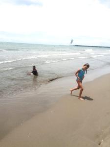 卡塔赫纳Exclusivo apartamento en Cartagena con vista al mar的和海里男人一起在海滩上散步的年轻女孩