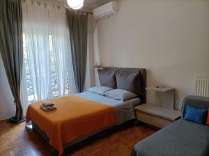 雅典Pagrati Park的一间卧室配有一张带橙色毯子和窗户的床。