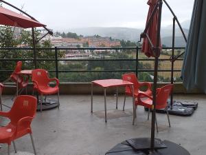 蒂内奥Albergue La Plaza的庭院配有红色的椅子、桌子和遮阳伞