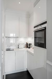泰根塞Villa Palazzo的白色的厨房配有白色的橱柜和微波炉