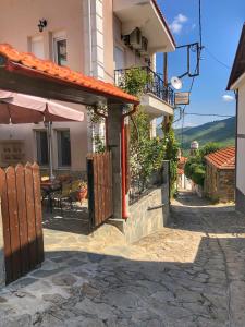 LechovoGuesthouse Monopati - Ξενώνας Μονοπάτι的房屋设有带桌子和遮阳伞的庭院