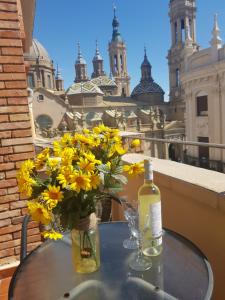 萨拉戈萨El BALCÓN de PILAR的一张桌子上一瓶黄色花瓶,配上一瓶葡萄酒