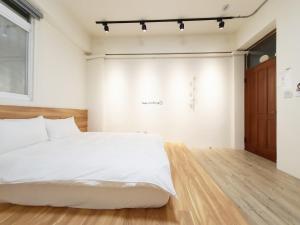 东港艾睏khùn行旅的卧室配有白色的床,铺有木地板