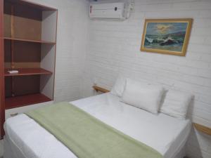 邦比尼亚斯Apartamento estilo chalé - Enxaimel的卧室配有白色的床和墙上的绘画作品