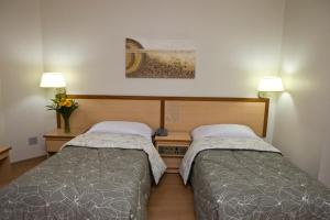 圣保罗奥古斯塔大道酒店的配有两盏灯的小房间内的两张床