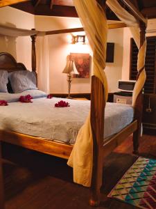 尼格瑞尔坎塔流火酒店的一间卧室配有一张带红色鲜花的天蓬床。