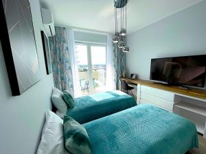 弗罗茨瓦夫Apartament z tarasem i widokiem na Odrę的一间卧室设有两张床、一台电视和一扇窗户。