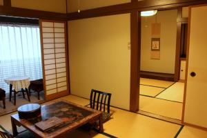 ŌwaniHistorical Ryokan SENYUKAN的客房设有桌椅和窗户。