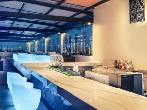 万隆美居万隆市中心酒店的酒吧设有白色凳子和酒精饮品瓶