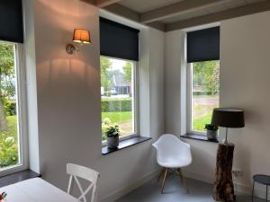 heinkenszandB&B Boerderij De Vaete - Duurzaam genieten in de zak van Zuid-Beveland的客房设有3扇窗户、白色椅子和灯