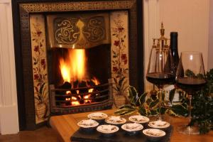 IrebyWoodlands Country House & Cottage的壁炉,桌子上放着一些纸杯蛋糕和酒杯