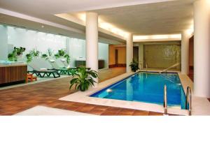 卡拉德费斯特拉特Ballesol Costablanca Senior Resort mayores de 55 años的大堂的游泳池配有桌椅