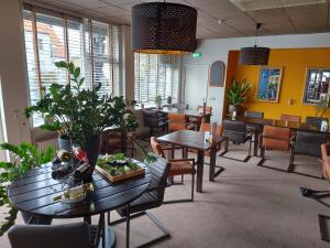 斯容代克Hotel de Zwaan的用餐室配有桌椅和植物
