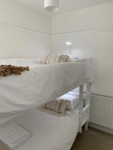 布罗德斯泰'Sandy Bottom' Broadstairs by the beach的白色的床、白色床单和枕头