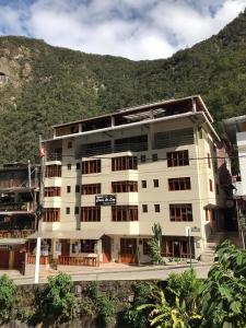 马丘比丘Casa De Luz Hotel的一座白色的大建筑,背景是一座山