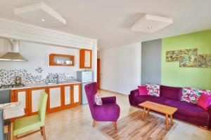卡斯Çınarlar Apart Hotel KAŞ的一间带紫色沙发的客厅和一间厨房