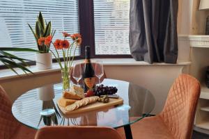 佩恩顿Modern and Spacious 4 Bedroom House, Hot Tub, Wifi, Netflix, Parking的玻璃桌,带一瓶葡萄酒和葡萄