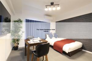 福冈The Grand Residence Hotel Hakata的一间卧室配有一张床、一张桌子和一张桌子